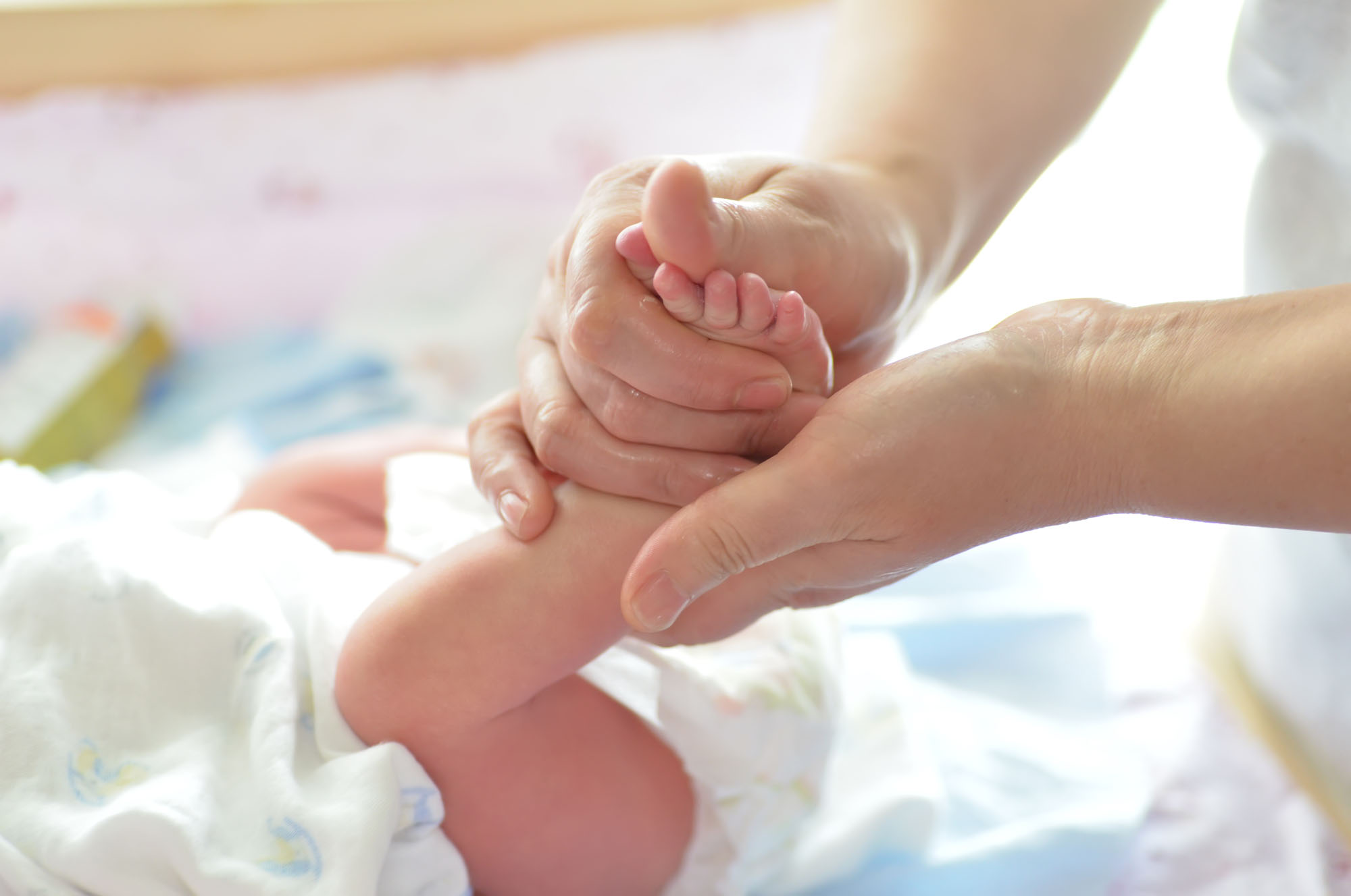 Mother massaging her child’s foot, shallow focus