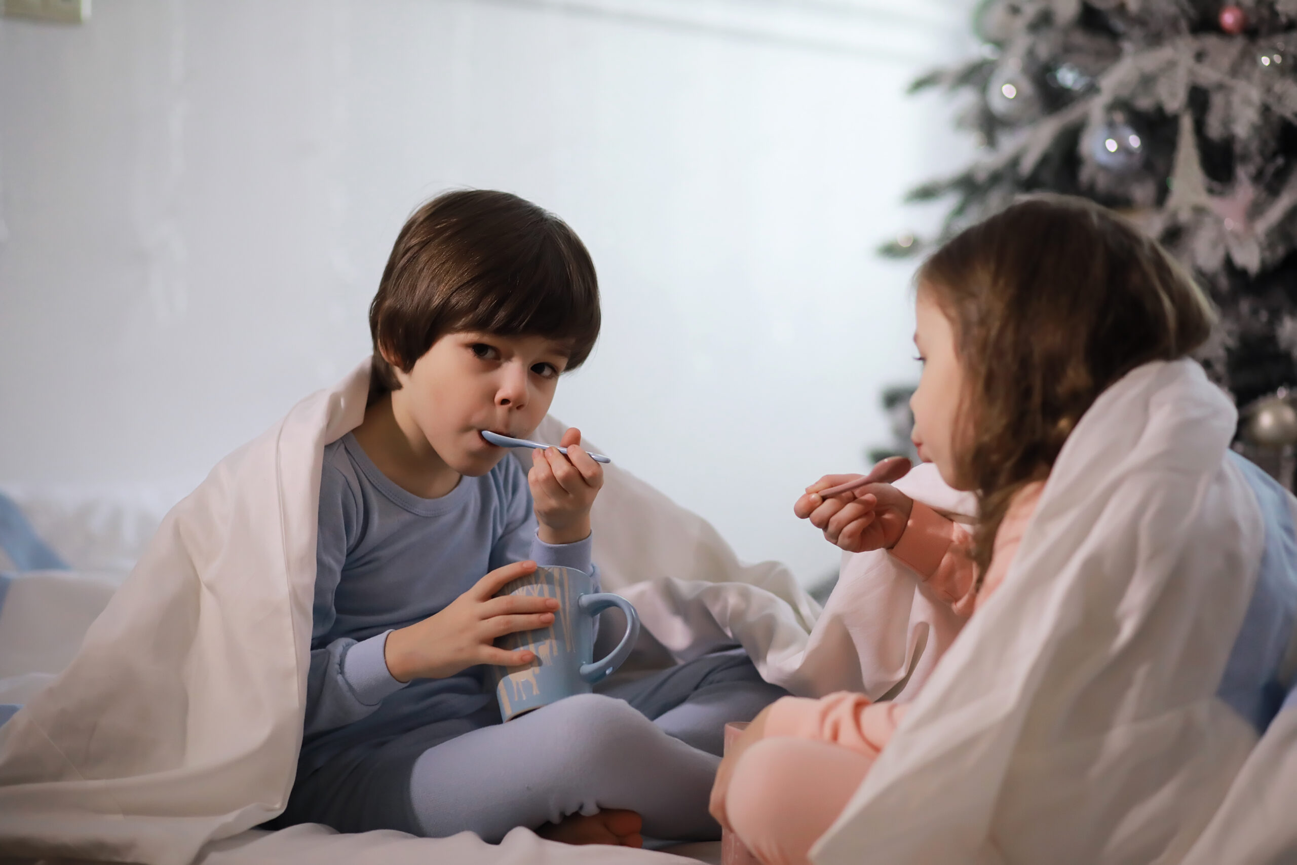 A family with children having fun on the bed under the covers du